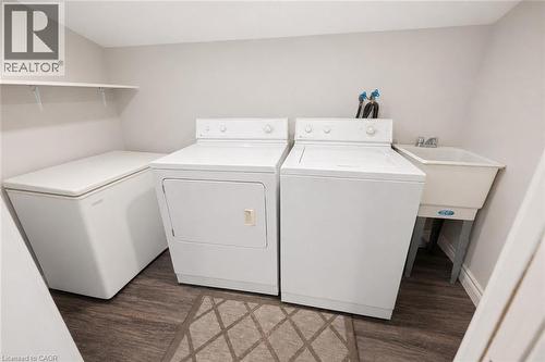 Dedicated utility room featuring a laundry tub, overhead shelving, and wood-finish flooring - 100 Memorial Crescent, Guelph, ON - Indoor Photo Showing Laundry Room