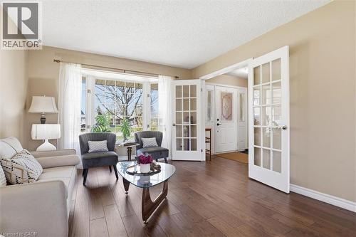 Spacious living area featuring rich wood-finish flooring, a large bay window, and French doors - 113 Glenecho Court, Waterloo, ON - Indoor Photo Showing Living Room