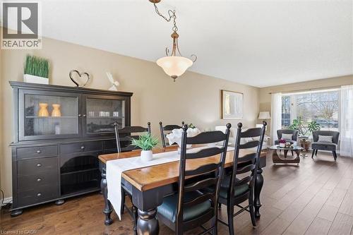 Open concept living and dining areas featuring wood-finish flooring, neutral wall tones, a large bay window, and a decorative chandelier - 113 Glenecho Court, Waterloo, ON - Indoor Photo Showing Dining Room