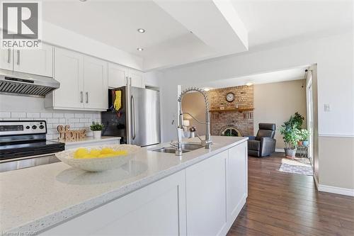 Bright kitchen featuring a center island with sink, white shaker cabinetry, stainless steel appliances, and subway tile backsplash - 113 Glenecho Court, Waterloo, ON - Indoor Photo Showing Kitchen With Fireplace With Double Sink