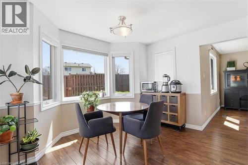 Dining area with bay windows, wood-finish flooring, a two-tone wall treatment, and a semi-flush ceiling light - 113 Glenecho Court, Waterloo, ON - Indoor Photo Showing Dining Room