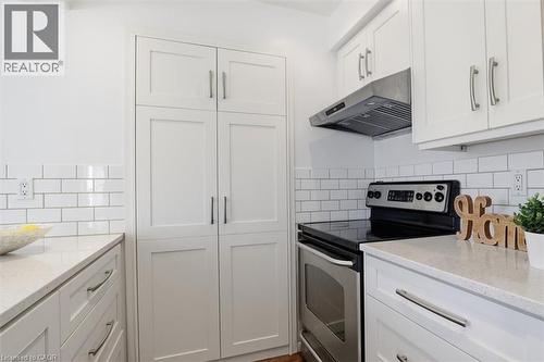 Kitchen featuring white shaker-style cabinetry, light-toned countertops, and a white subway tile backsplash - 113 Glenecho Court, Waterloo, ON - Indoor Photo Showing Kitchen