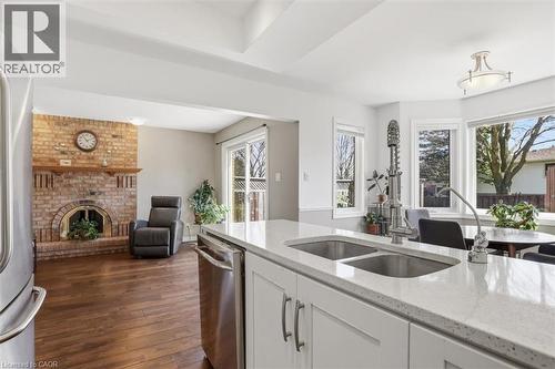 Kitchen island featuring a dual stainless steel sink and light-toned solid surface countertop - 113 Glenecho Court, Waterloo, ON - Indoor Photo Showing Kitchen With Fireplace With Double Sink