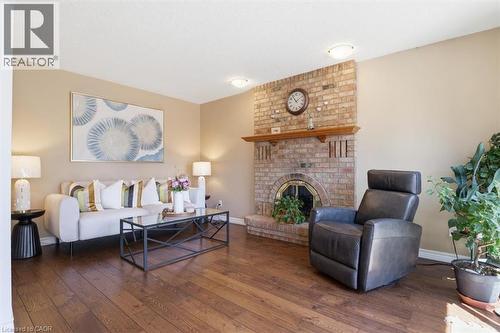 Spacious living area featuring a brick fireplace with a wood mantle, wood-finish flooring, and neutral wall tones - 113 Glenecho Court, Waterloo, ON - Indoor Photo Showing Living Room With Fireplace