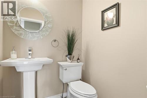 Pedestal sink with chrome faucet, complemented by a decorative round mirror - 113 Glenecho Court, Waterloo, ON - Indoor Photo Showing Bathroom