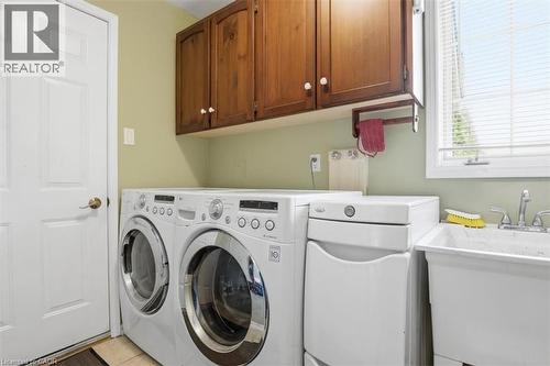 Dedicated laundry area featuring a utility sink, wood cabinetry, and a window with blinds - 113 Glenecho Court, Waterloo, ON - Indoor Photo Showing Laundry Room