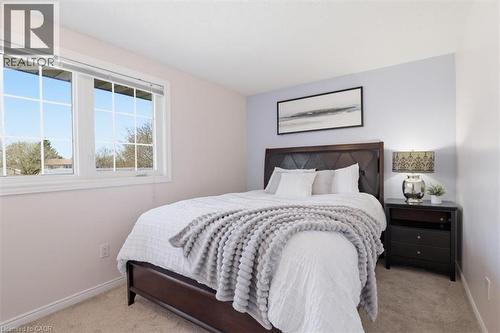 Bedroom featuring light carpeting, a large window with white framing and grilles, and soft lavender wall tones - 113 Glenecho Court, Waterloo, ON - Indoor Photo Showing Bedroom
