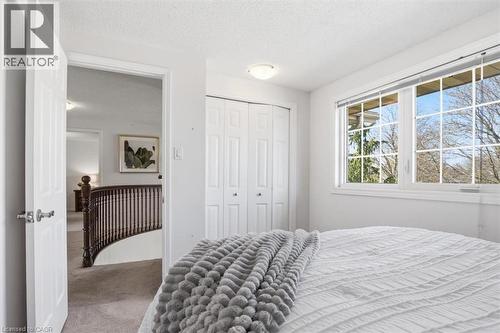 Bright room featuring a large window with grid pattern, white bi-fold closet doors, and recessed lighting - 113 Glenecho Court, Waterloo, ON - Indoor Photo Showing Bedroom
