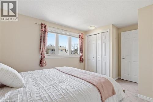 Carpeted room with a wide window, bi-fold closet doors, and neutral wall paint - 113 Glenecho Court, Waterloo, ON - Indoor Photo Showing Bedroom