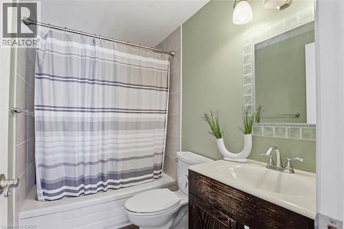 Bathroom featuring a shower-tub combination with tiled surround, a toilet, and a vanity with a wood-finish cabinet and integrated sink - 113 Glenecho Court, Waterloo, ON - Indoor Photo Showing Bathroom
