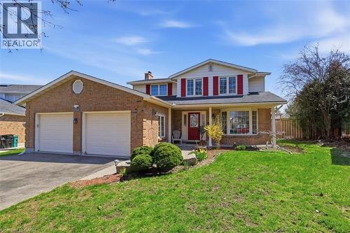 Brick exterior residence featuring a two-car garage with white doors, a red front entry door, and red window shutters - 113 Glenecho Court, Waterloo, ON - Outdoor With Deck Patio Veranda With Facade