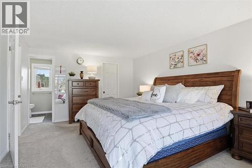Spacious bedroom featuring light neutral wall paint, soft carpet flooring, and a solid wood bed frame with matching nightstands - 113 Glenecho Court, Waterloo, ON - Indoor Photo Showing Bedroom