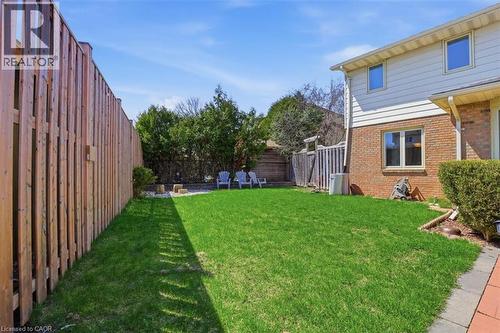 Expansive backyard featuring a green lawn, wood privacy fencing, and mature perimeter trees - 113 Glenecho Court, Waterloo, ON - Outdoor