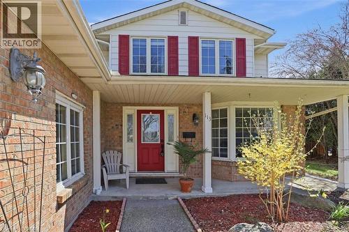 Brick facade with a covered entry, featuring a vibrant red front door with decorative glass - 113 Glenecho Court, Waterloo, ON - Outdoor