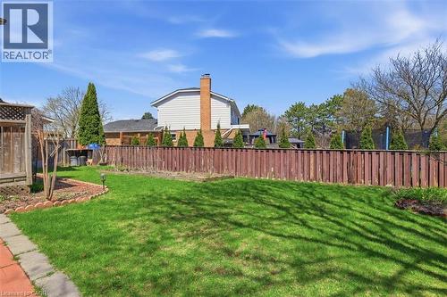 Expansive backyard featuring a lush green lawn, full privacy fencing, and mature perimeter trees - 113 Glenecho Court, Waterloo, ON - Outdoor