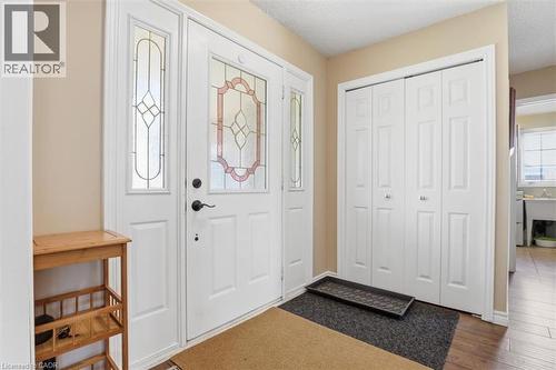 Entryway featuring a white door with decorative glass inserts and a matching sidelight, bi-fold closet doors, and wood-finish flooring - 113 Glenecho Court, Waterloo, ON - Indoor Photo Showing Other Room