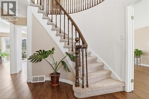 Curved staircase with wood-finish handrail and balusters, carpeted treads, and wood-finish flooring in the entryway - 113 Glenecho Court, Waterloo, ON - Indoor Photo Showing Other Room