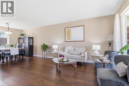 Open-concept living area featuring wood-finish flooring, neutral wall tones, and a large bay window with white drapery - 113 Glenecho Court, Waterloo, ON - Indoor Photo Showing Living Room