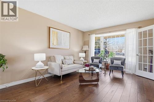 Spacious living area featuring wood-finish flooring, a bay window with ample natural light, and French doors - 113 Glenecho Court, Waterloo, ON - Indoor Photo Showing Living Room