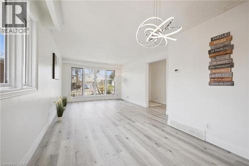 Bright interior space featuring light wood-finish flooring, white walls, and a modern circular chandelier - 27 Silverspring Crescent, Kitchener, ON - Indoor