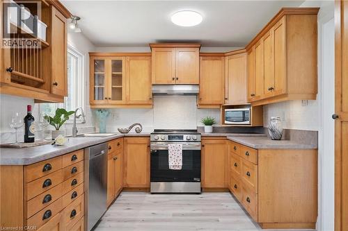 U-shaped kitchen featuring light wood cabinetry, light gray countertops, a stainless steel range, and a built-in dishwasher - 27 Silverspring Crescent, Kitchener, ON - Indoor Photo Showing Kitchen