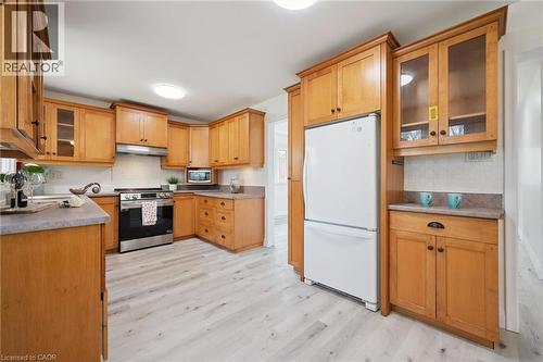 Kitchen featuring abundant wood cabinetry, light wood-finish flooring, a stainless steel range with overhead ventilation, and a white subway tile backsplash - 27 Silverspring Crescent, Kitchener, ON - Indoor Photo Showing Kitchen