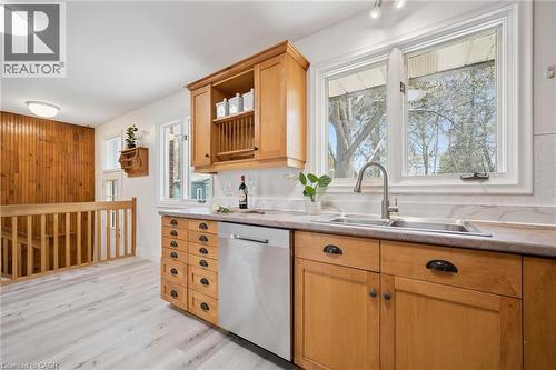 Kitchen featuring warm wood cabinetry, a double basin stainless steel sink, a stainless steel dishwasher, light-toned countertops, and a white tile backsplash - 27 Silverspring Crescent, Kitchener, ON - Indoor Photo Showing Kitchen With Double Sink