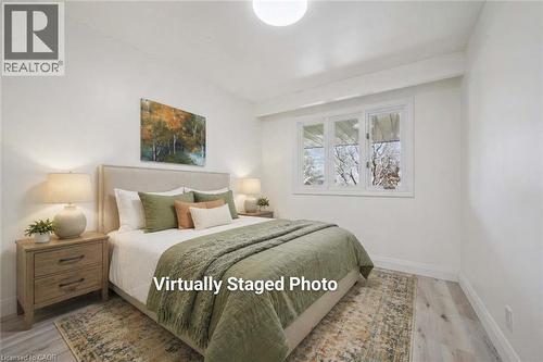 Bright interior space featuring a multi-pane window, light-toned wood-finish flooring, and white baseboards - 27 Silverspring Crescent, Kitchener, ON - Indoor Photo Showing Bedroom