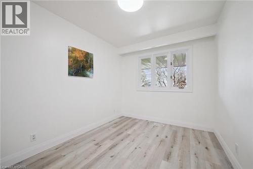 Bright interior space featuring light wood-finish flooring, white baseboards, and a triple-pane window - 27 Silverspring Crescent, Kitchener, ON - Indoor Photo Showing Other Room