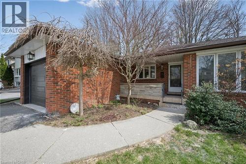 Brick exterior featuring a dark garage door, large picture windows, and a concrete walkway - 27 Silverspring Crescent, Kitchener, ON - Outdoor
