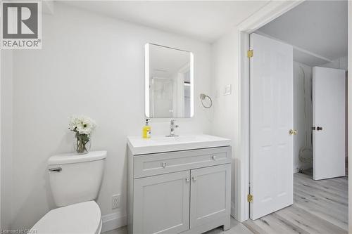 Bright bathroom featuring a contemporary vanity with an integrated sink, illuminated mirror, and light wood-finish flooring - 27 Silverspring Crescent, Kitchener, ON - Indoor Photo Showing Bathroom