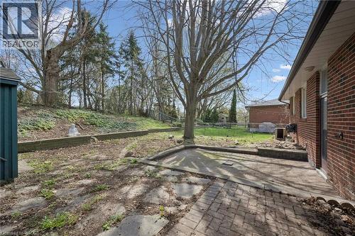 Expansive backyard featuring a brick paver patio, established trees, a sloped natural landscape, and a utility shed - 27 Silverspring Crescent, Kitchener, ON - Outdoor
