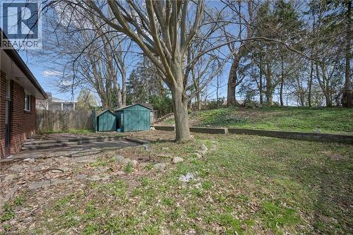 Expansive outdoor area featuring a mature tree, terraced landscaping with retaining walls, and a brick-sided structure - 27 Silverspring Crescent, Kitchener, ON - Outdoor