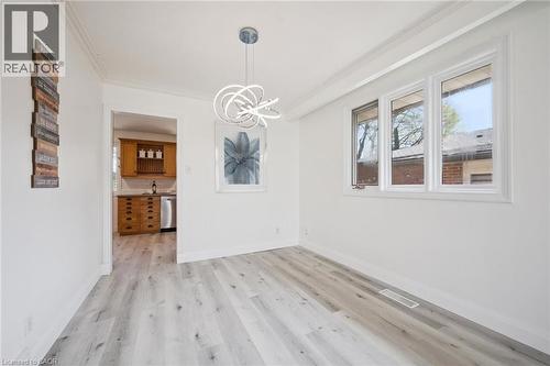 Dining area featuring wood-finish flooring, a contemporary ceiling light fixture, crown molding, and multiple windows - 27 Silverspring Crescent, Kitchener, ON - Indoor Photo Showing Other Room