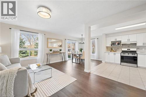 Living room featuring light wood-type flooring, a chandelier, and healthy amount of natural light - 649 Doon South Drive, Kitchener, ON - Indoor Photo Showing Other Room