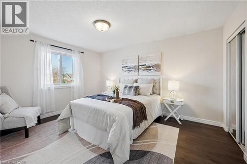 Bedroom featuring dark wood-type flooring, a textured ceiling, and a closet - 649 Doon South Drive, Kitchener, ON - Indoor Photo Showing Bedroom