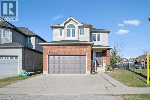 Traditional home with brick siding, asphalt driveway, a front lawn, and an attached garage - 649 Doon South Drive, Kitchener, ON - Outdoor