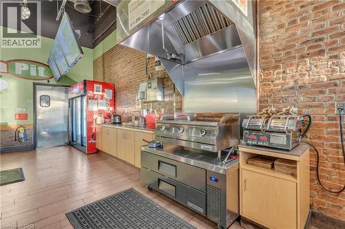 Commercial kitchen featuring brick wall accents and wood-finish flooring - 589 Fairway Road S, Kitchener, ON 