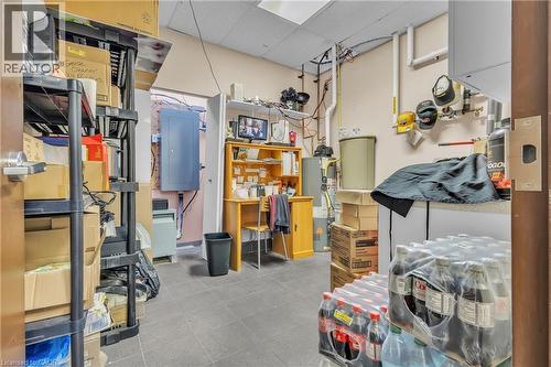 Commercial utility room featuring a built-in wooden desk, a water heater, visible plumbing, and dropped ceiling tiles - 589 Fairway Road S, Kitchener, ON 