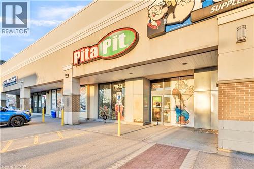 Commercial facade featuring multiple storefronts, brick accents, and a paved parking area - 589 Fairway Road S, Kitchener, ON 