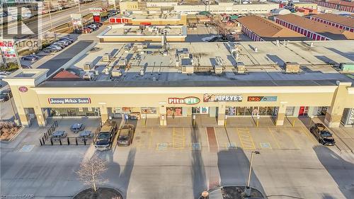Commercial retail building featuring multiple storefronts, a prominent sign structure, and an expansive paved parking area - 589 Fairway Road S, Kitchener, ON 