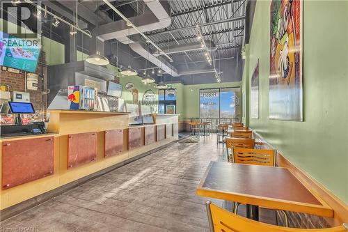 Commercial interior featuring light green walls, exposed ceiling ductwork, track lighting, and tiled flooring - 589 Fairway Road S, Kitchener, ON 