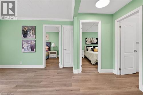 Wood-finish flooring extends throughout this interior space, featuring light green walls and white trim - 36 Mahony Avenue, Hamilton, ON - Indoor
