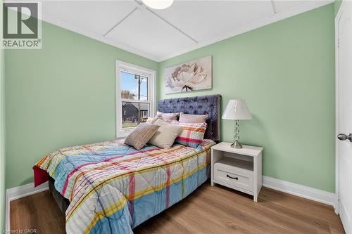 Room featuring wood-finish flooring, light green walls, white trim, and a single window with white framing - 36 Mahony Avenue, Hamilton, ON - Indoor Photo Showing Bedroom