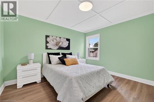 Bedroom featuring light green walls, wood-finish flooring, a single window, white trim, and a ceiling light fixture - 36 Mahony Avenue, Hamilton, ON - Indoor Photo Showing Bedroom