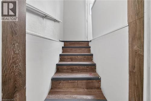 Staircase with wood-finish treads and risers, complemented by a white wall with a protective handrail - 36 Mahony Avenue, Hamilton, ON - Indoor Photo Showing Other Room