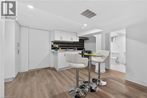 Modern kitchenette featuring white cabinetry, a dark striped backsplash, and stainless steel fixtures - 36 Mahony Avenue, Hamilton, ON - Indoor