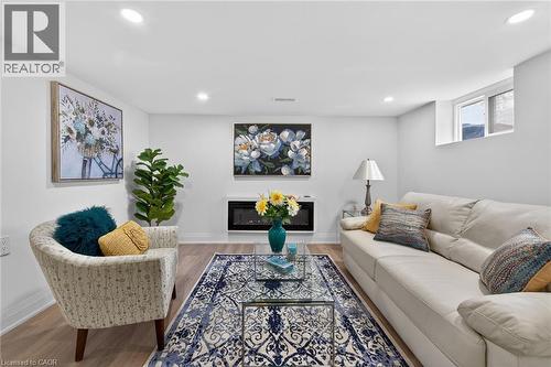 Recessed lighting illuminates a room featuring light wood-finish flooring, a wall-mounted electric fireplace, and a high-set window - 36 Mahony Avenue, Hamilton, ON - Indoor Photo Showing Living Room