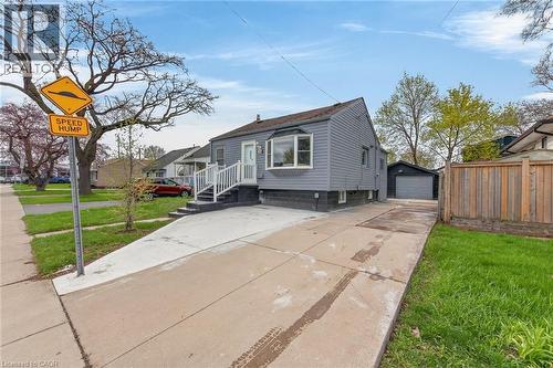 Grey siding exterior with white trim, front entry porch with white railings, bay window, and a detached single-car garage - 36 Mahony Avenue, Hamilton, ON - Outdoor
