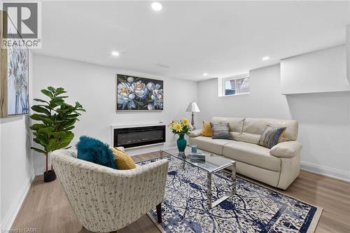 Living area featuring wood-finish flooring, recessed lighting, a modern electric fireplace, and a window providing natural light - 36 Mahony Avenue, Hamilton, ON - Indoor Photo Showing Living Room With Fireplace